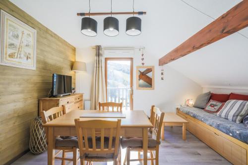 sala de estar con mesa y sofá en Residence Les Chalets d'Aurouze - maeva Home, en La Joue du Loup