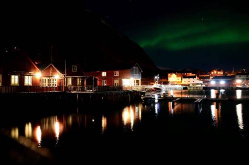 a green light in the sky over a marina at night at Kræmmervika Havn in Ballstad