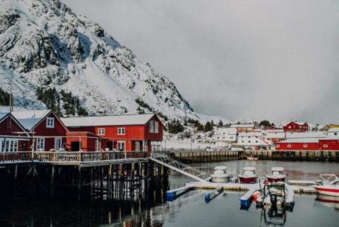 a marina with boats in the water next to a mountain at Kræmmervika Havn in Ballstad
