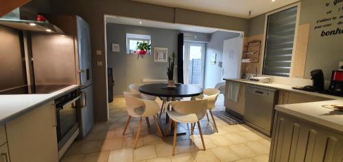 eine Küche mit einem Tisch und weißen Stühlen in der Unterkunft La Maison Clémenso in Cluny