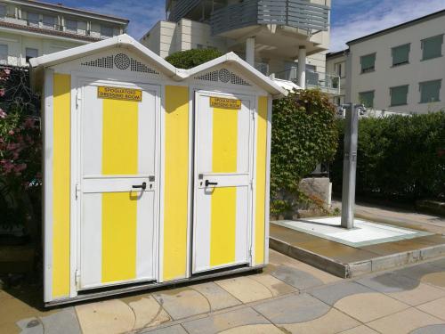 a yellow and white outhouse with doors on a sidewalk at Hesperia Hotel & Residence in Lido di Jesolo