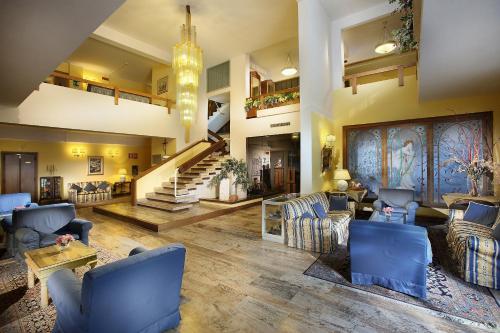 a large living room with blue chairs and a staircase at Hotel Mirò Montecatini Terme in Montecatini Terme