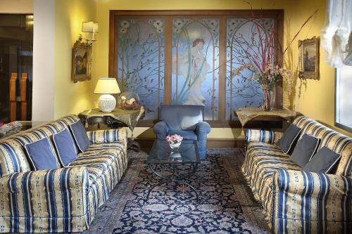 a living room with two couches and a man sitting in a chair at Hotel Mirò Montecatini Terme in Montecatini Terme