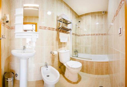 a bathroom with a toilet and a sink and a tub at Hotel Arce in Baiona