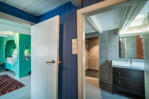 a bathroom with blue walls and a sink and a mirror at Håholmen - by Classic Norway Hotels in Karvåg