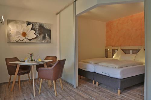 Schlafzimmer mit einem Bett und einem Tisch sowie einem Tisch und Stühlen in der Unterkunft Alpenstern Finy, Bio-Gästehaus in Oy-Mittelberg