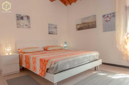 a white bedroom with a bed with an orange blanket at The Comfort Apartment in Montagnana
