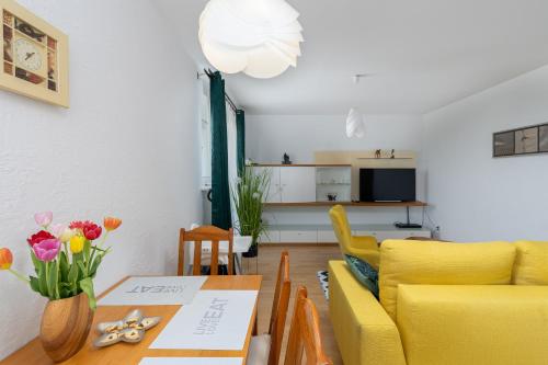 ein Wohnzimmer mit einem Tisch und gelben Stühlen in der Unterkunft ap4you Tauron Cracow in Krakau
