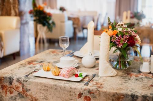a table with a plate of food and a vase of flowers at GRAND OTRADA Hotel Resort & SPA in Odesa