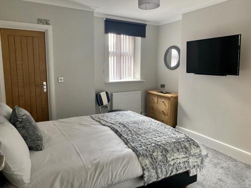 a bedroom with a bed and a flat screen tv at Jeffersons Hotel & Serviced Apartments in Barrow in Furness