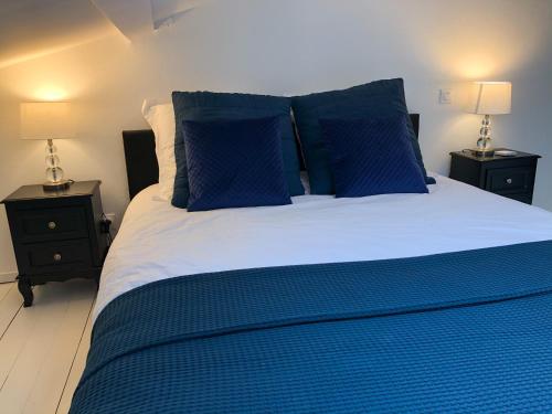 a blue bed with blue pillows and two night stands at Appart Luxe Atypique in Épinal