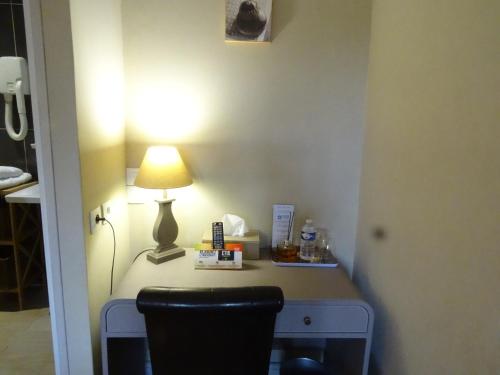 a room with a desk with a lamp and a chair at Logis Hôtel Restaurant Spa L'auberge Du President in Cormeilles
