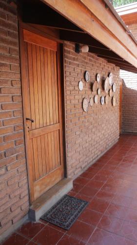 a brick building with a wooden door and a brick wall at Lujan De Cuyo B&B in Ciudad Lujan de Cuyo
