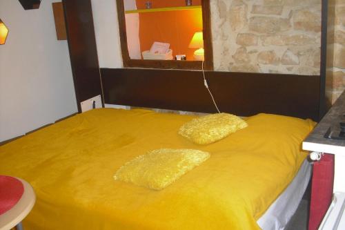 Una cama amarilla con dos almohadas amarillas. en La melonnière, en Gordes