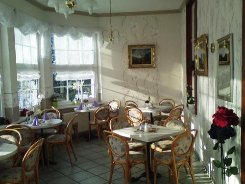 une salle à manger avec tables, chaises et fenêtres dans l'établissement Villa HarzFokus - #Hotel#Pension#Frühstück, à Wernigerode