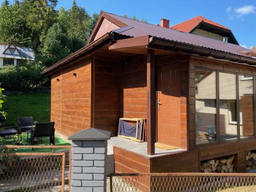 drewniany domek z werandą i ogrodzeniem w obiekcie Domek Przy Stoku - Słotwiny w mieście Krynica Zdrój
