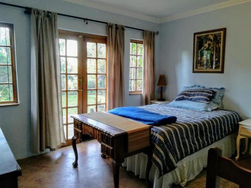 a bedroom with a bed with a table and windows at Tucked away in the tree tops in Hillcrest