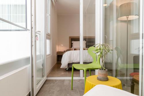 Habitación con silla verde y cama en Miraflores a tu Estilo, en Lima