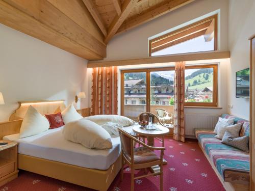 a bedroom with a bed and a table and a window at Hotel Pinzger Tux in Tux