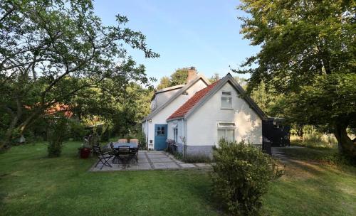 ein kleines weißes Haus mit einer Terrasse im Hof in der Unterkunft Cottage Duinroos - Dune Rose in Oostvoorne