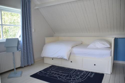 a small bedroom with a white bed and a window at Cottage Duinroos - Dune Rose in Oostvoorne