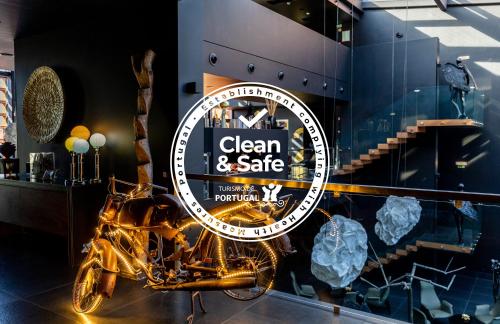 een bord voor een schone en veilige winkel met een motorfiets op de display bij Evidencia Belverde Hotel in Amora