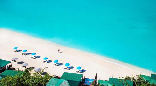 a group of umbrellas and chairs on a beach at COCOS Hotel Antigua - All Inclusive - Adults Only in Bolans