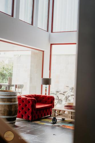 a red couch sitting in a room with windows at Amoras Country House Hotel in Proença-a-Nova
