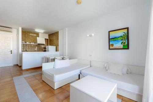 a white living room with a couch and a table at Apartamentos San Antonio Beach in San Antonio Bay