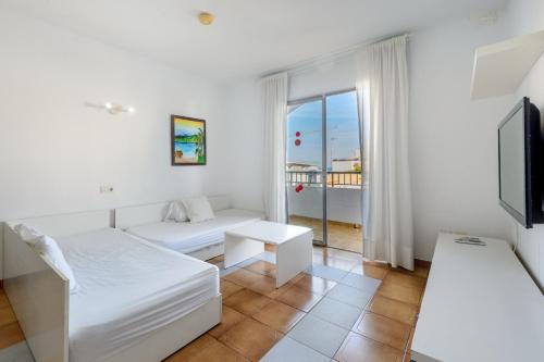 a white room with a bed and a tv at Apartamentos San Antonio Beach in San Antonio Bay