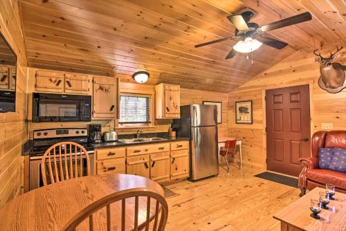 a kitchen with wooden walls and a ceiling fan at Parsons Cabin with Fire Pit and River Access! in Parsons