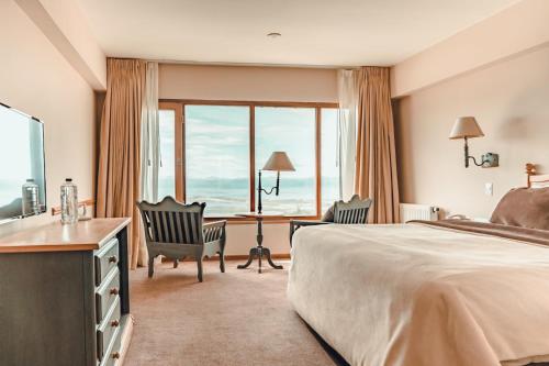 um quarto de hotel com uma cama e uma secretária com cadeiras em Wyndham Garden Ushuaia Hotel del Glaciar em Ushuaia