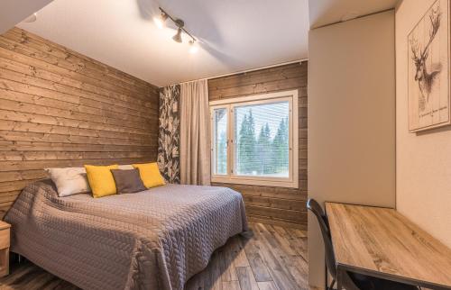 Schlafzimmer mit einer Wand mit Holzakzenten und einem Bett in der Unterkunft RukaValley Unique47 Ski In - Ski Out in Ruka