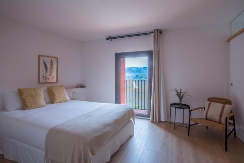 a bedroom with a bed and a window and a chair at Hotel Rural Mas de l'Illa in Tivissa