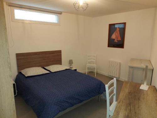 um quarto com uma cama azul e uma mesa de madeira em Choletais forever... em Cholet