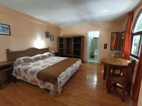 Un dormitorio con una cama y una mesa. en Hotel San Angel, en Puebla