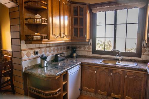 a kitchen with wooden cabinets and a sink at VILLA LAS CUEVAS in Tías