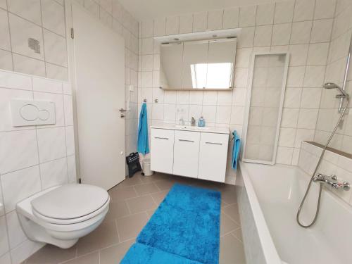 a bathroom with a white toilet and a blue rug at Ferienwohnung Karola beim Legoland in Ichenhausen