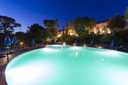 una grande piscina notturna con sedie e ombrelloni di Toscana Verde a Laterina