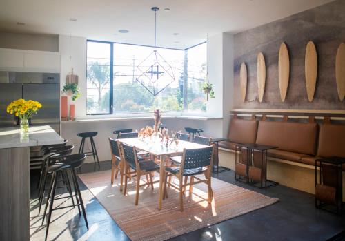 a dining room with a table and chairs and surfboards on the wall at Haven Coliving in Los Angeles
