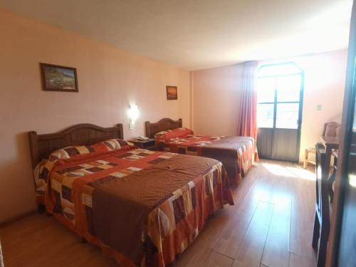 a hotel room with two beds and a window at Hotel San Angel in Puebla