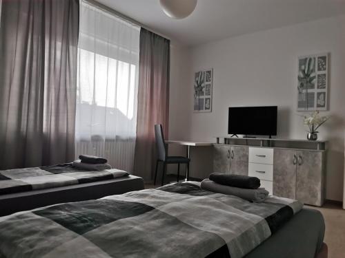 a bedroom with two beds and a desk and a tv at M&M Apartments in Augustdorf
