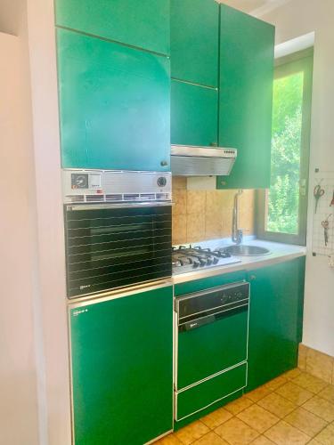 a green kitchen with a stove and a sink at Green Apartment in Albavilla