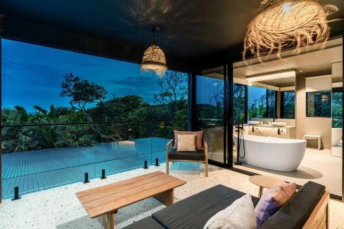 uma sala de estar aberta com uma banheira e uma grande janela em Ocean Suites Byron Bay em Byron Bay