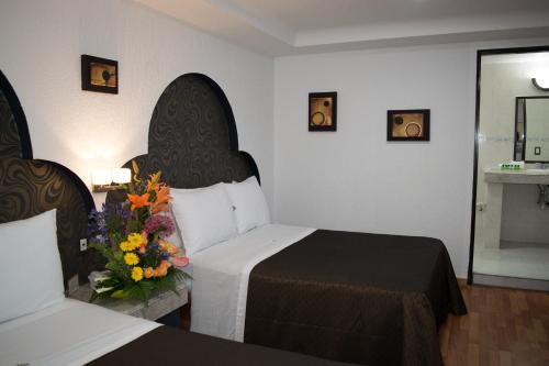 - une chambre d'hôtel avec 2 lits et un bouquet de fleurs dans l'établissement Hotel Santiago, à Puebla