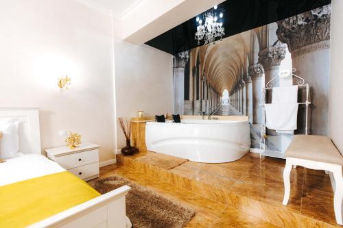 a bathroom with a white tub and a bed at Hotel Evianne Boutique in Galaţi