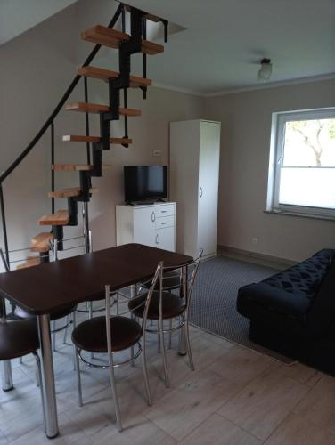 a living room with a table and a spiral staircase at Gajówka in Radków