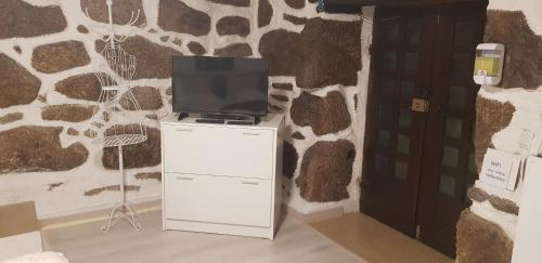 - une télévision installée au-dessus d'un réfrigérateur blanc dans l'établissement Casa Bento Teixeira, à Belmonte