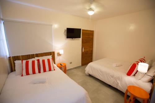 a bedroom with two beds and a tv on the wall at El Caite San Juan del Sur in San Juan del Sur
