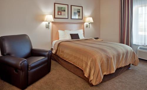 a hotel room with a bed and a chair at Candlewood Suites Olathe, an IHG Hotel in Olathe